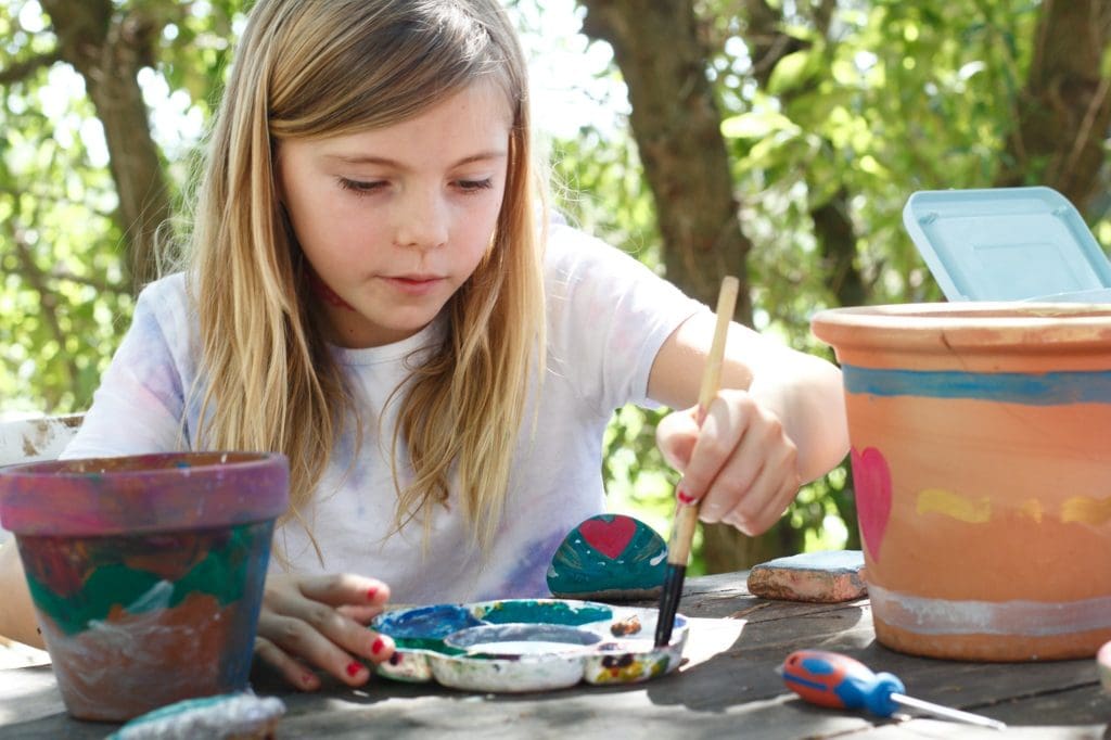 Girl painting plant pots arts and crafts